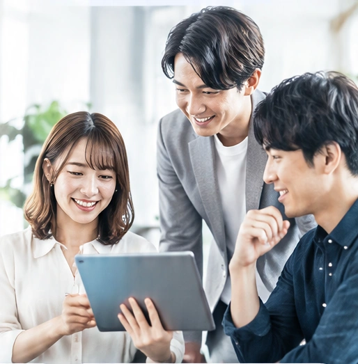 タブレットを囲み、笑顔で話し合うチーム